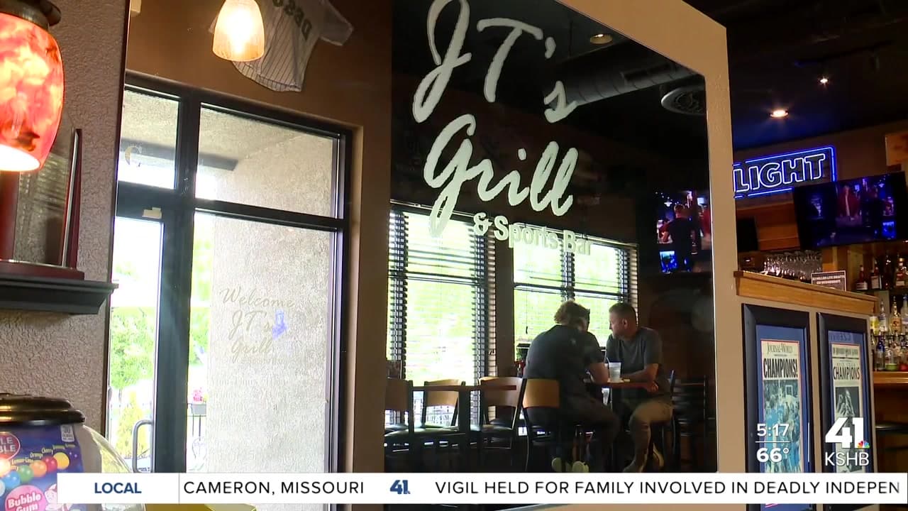 KSHBの報道映像に映るJT’sの店内。JT’s Grill & Sports Barの文字があるガラスと、テーブルやカウンターが見える