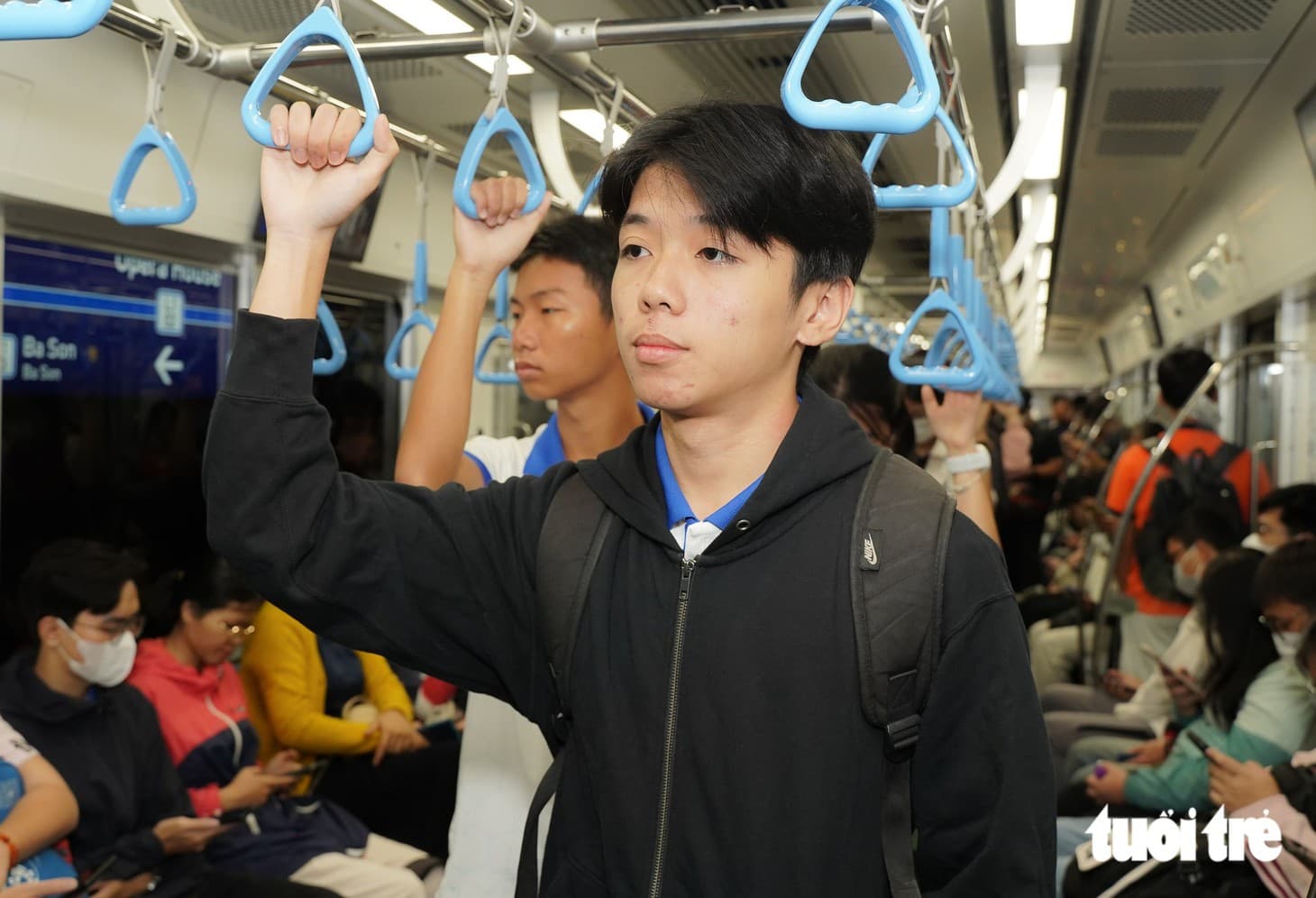 メトロ車内でつり革につかまる学生のブイ・ザー・カンさん。Tuổi Trẻの取材写真